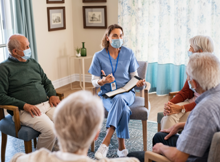 Mental health nurse sits with elderly people in a group session.