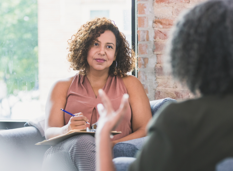 Psychiatrist sitting opposite a patient, holding a clipboard.