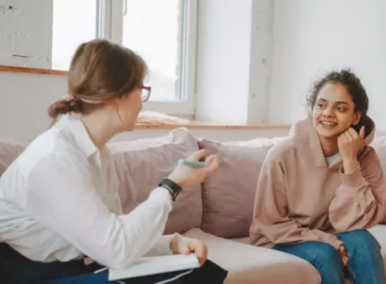 Psychiatrist and patient sitting on a couch talking.
